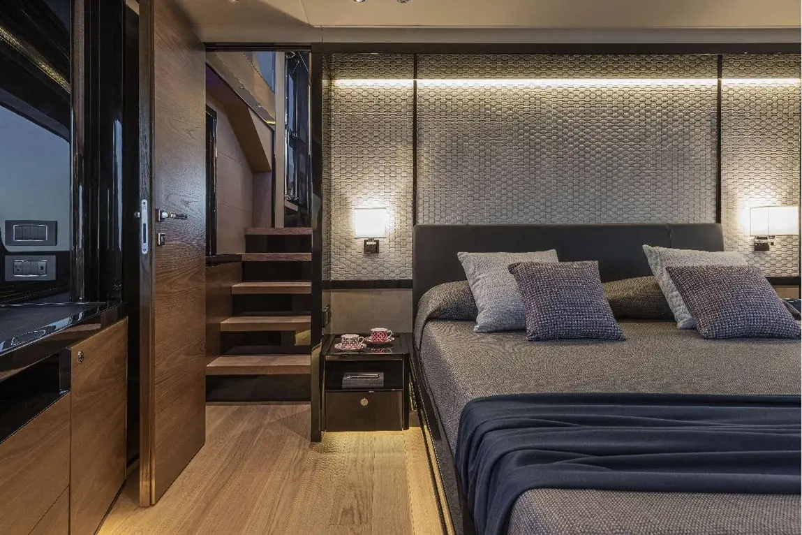 Modern bedroom featuring a double bed with decorative pillows, wooden stairs, textured wall, and stylish lighting fixtures.